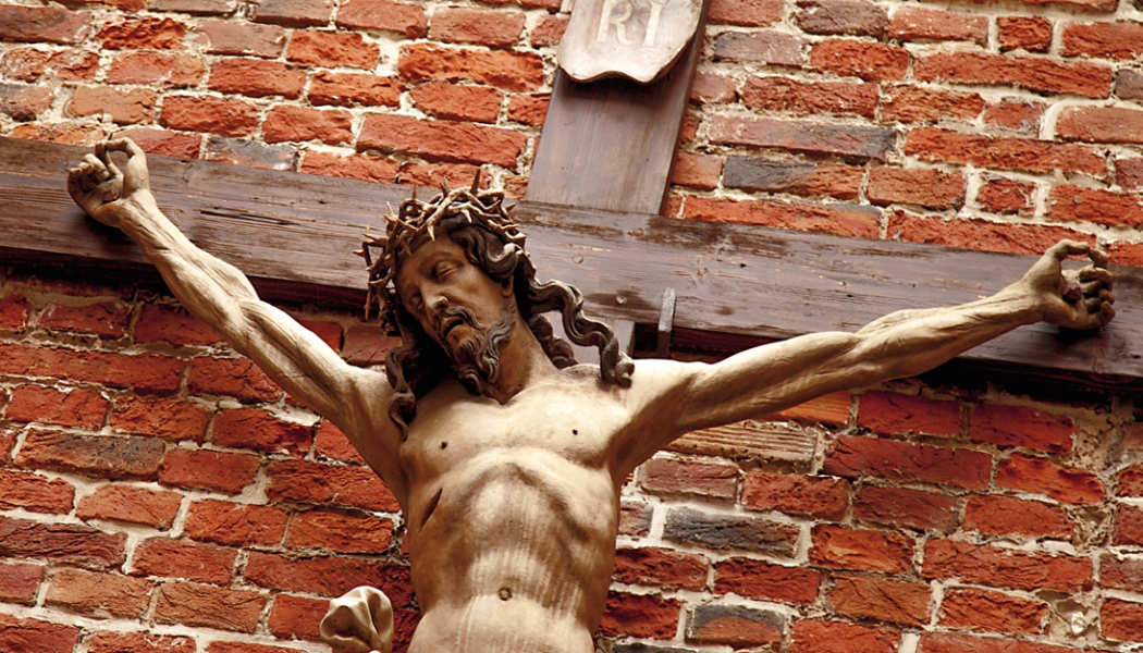 Wooden carving of Jesus crucifixion against a brick wall